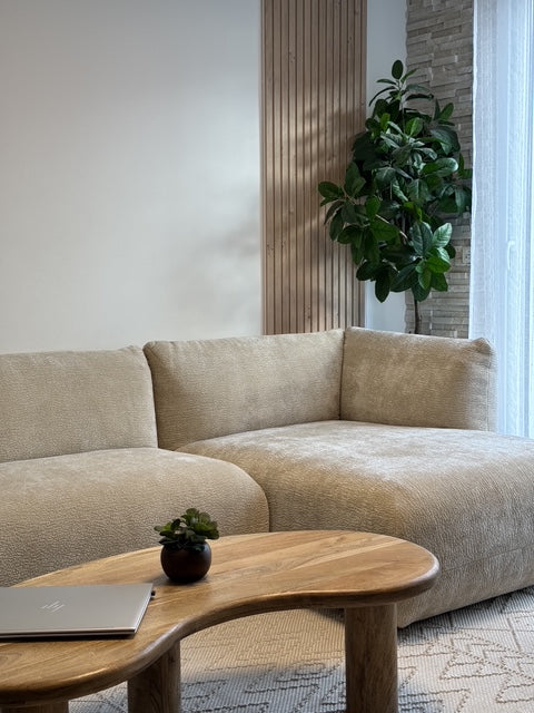 Canapé d'angle Sainte-Croix beige avec méridienne Paname Avenue et table basse en bois dans un salon client contemporain aux matières naturelles