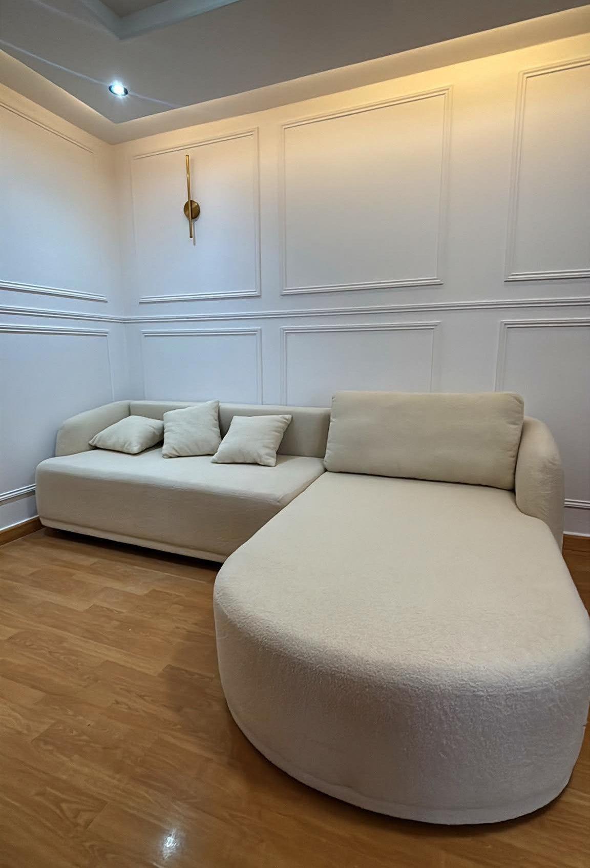 Canapé d'angle Charlot en tissu bouclette beige Paname Avenue avec méridienne arrondie dans un salon contemporain avec boiseries murales - retour client