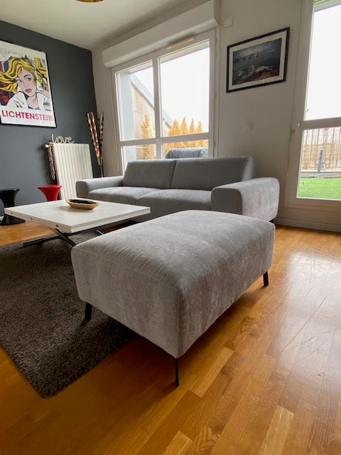Retour client du canapé droit 4 places Frochot en tissu chenille ainsi que le pouf Douai en gris discret de chez Paname Avenue en vue 3/4 dans un salon original et un parquet massif.