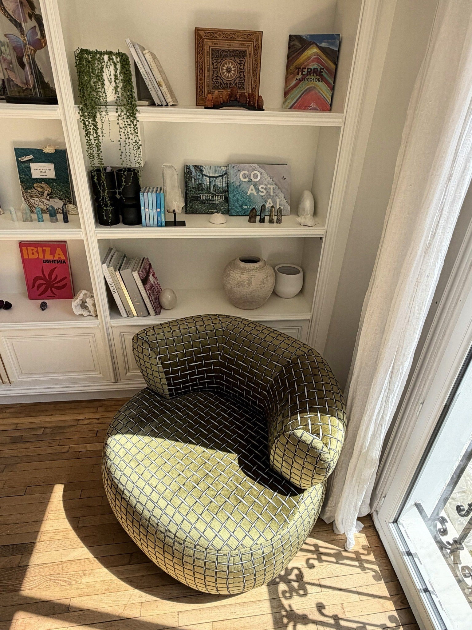 Fauteuil Montorgueil en velours lisse vert olive de chez Paname Avenue près d'une bibliothèque sur mesure et d'une fenêtre baignée de lumière - retour client