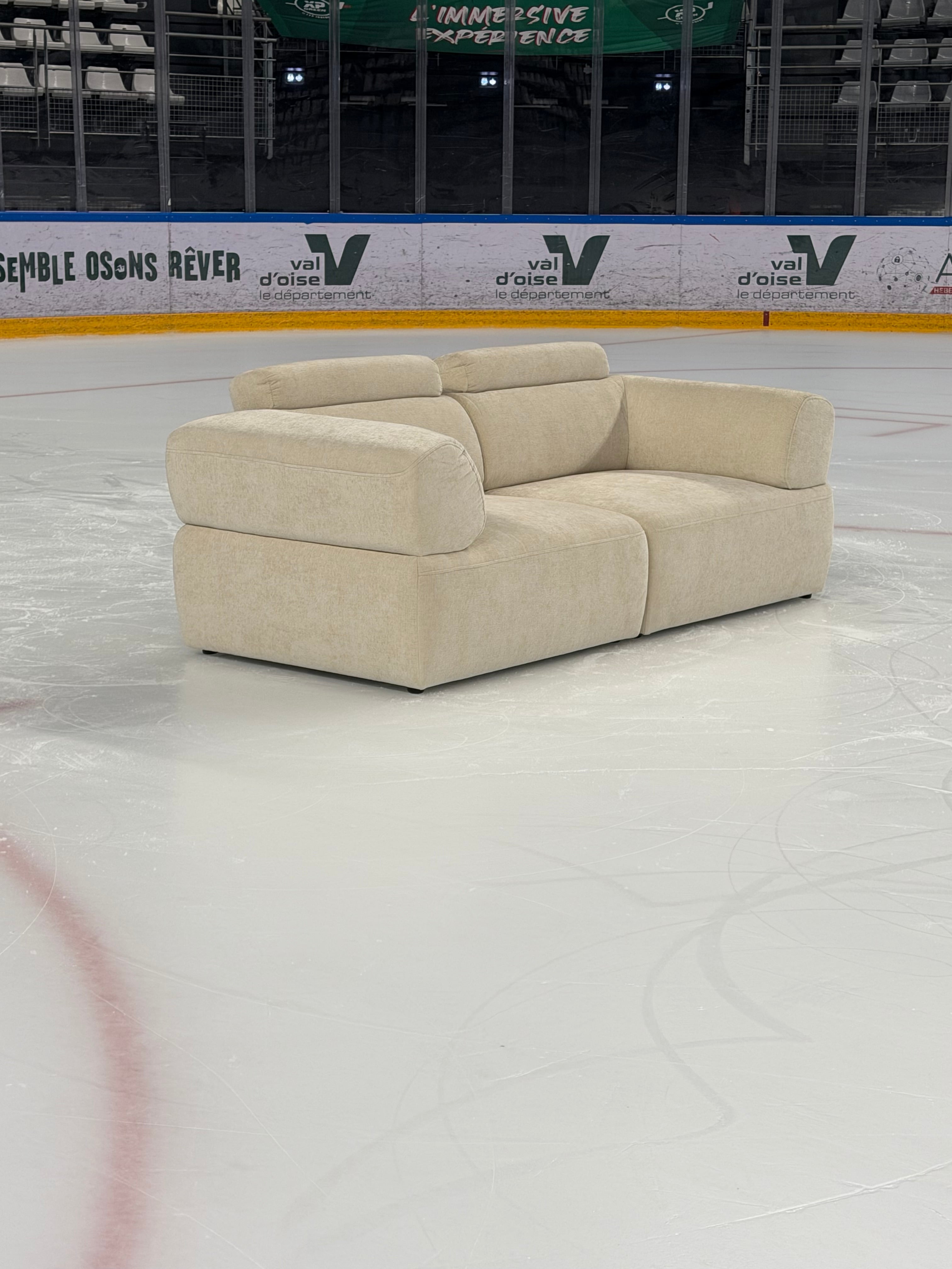 Canapé droit 3 places Réaumur en tissu chenille beige apaisé de chez Paname Avenue en vue 3/4 dans une patinoire pour le tournage d'une campagne marketing de la marque en présence d'une patineuse professionnelle.