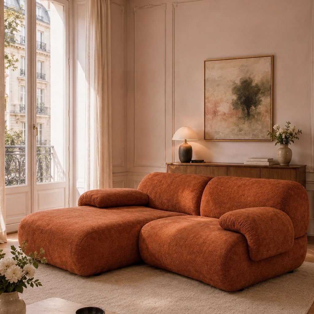 Canapé d'angle Pot-de-Fer en tissu chenille terracotta dans un salon haussmannien lumineux avec table basse en pierre, parquet point de Hongrie et ambiance chaleureuse