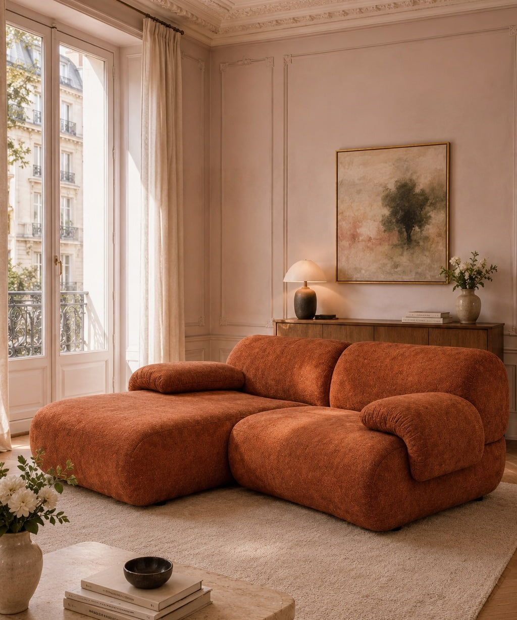 Canapé d'angle Pot-de-Fer en tissu chenille terracotta dans un salon haussmannien lumineux avec table basse en pierre, parquet point de Hongrie et ambiance chaleureuse