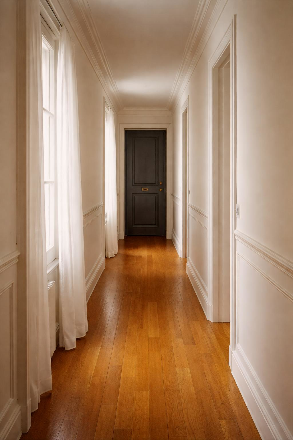 Couloir parisien blanc avec fenêtres et parquet en bois