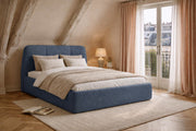 Lit coffre Rosiers en tissu chenille bleu de chez Paname Avenue dans une chambre mansardée parisienne avec poutres apparentes et balcon