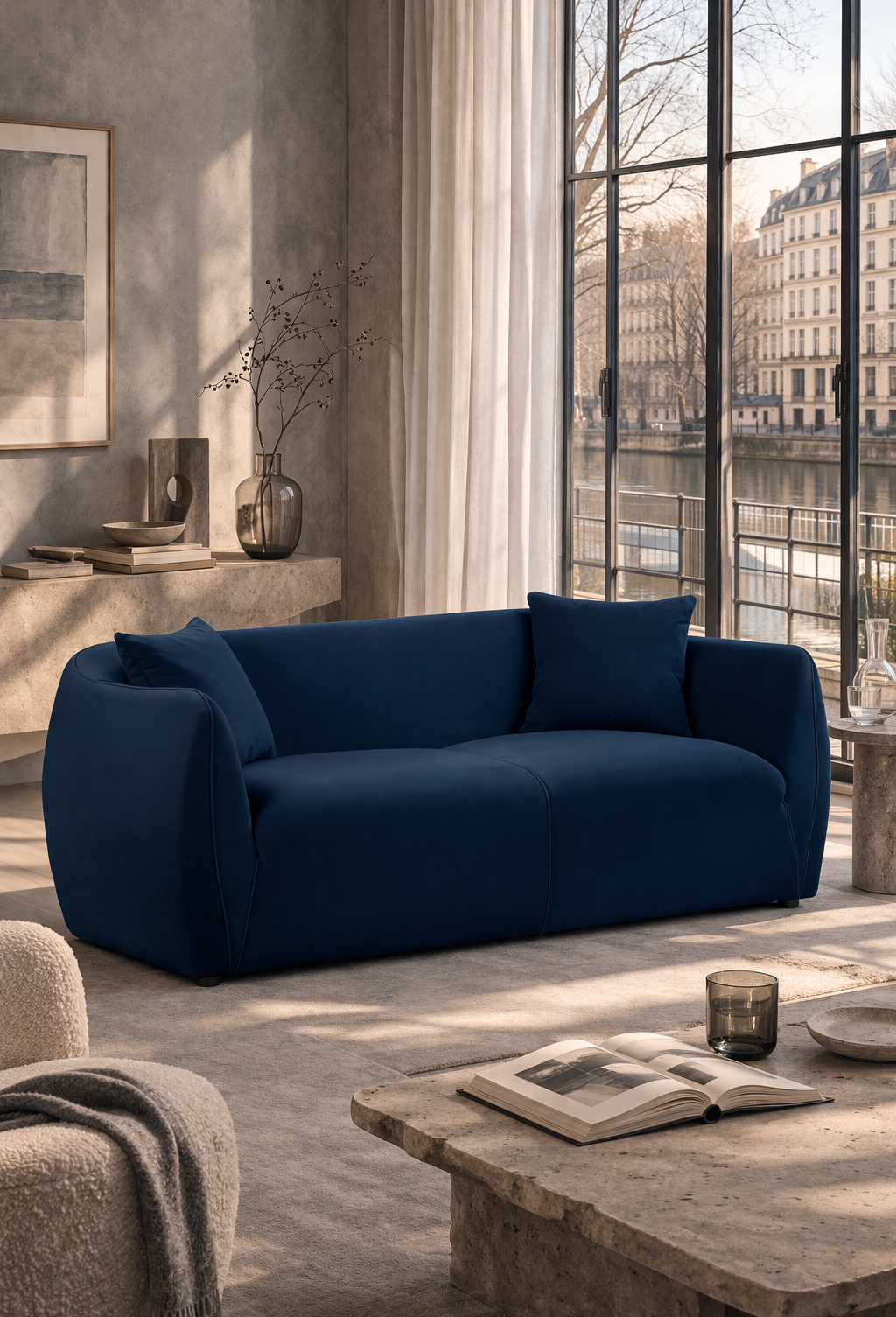 Canapé droit Faubourg Saint Martin de couleur bleu contrastant avec le salon dans les tons minéraux avec vue  par la baie vitrée surplombant  le canal Saint Martin