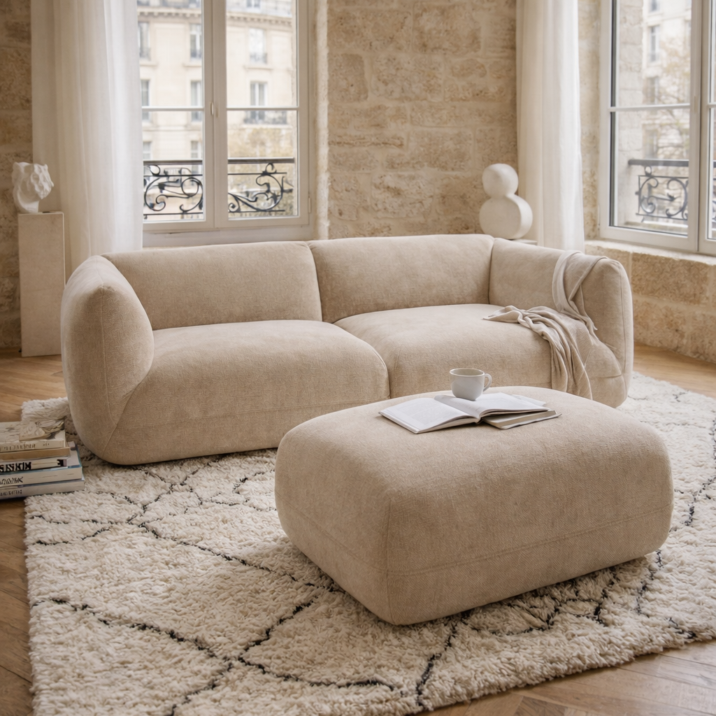 Canapé Portefoin et pouf Blainville sur un tapis berbère dans un décor d'intérieur parisien avec murs en pierre et parquet en point de Hongrie.