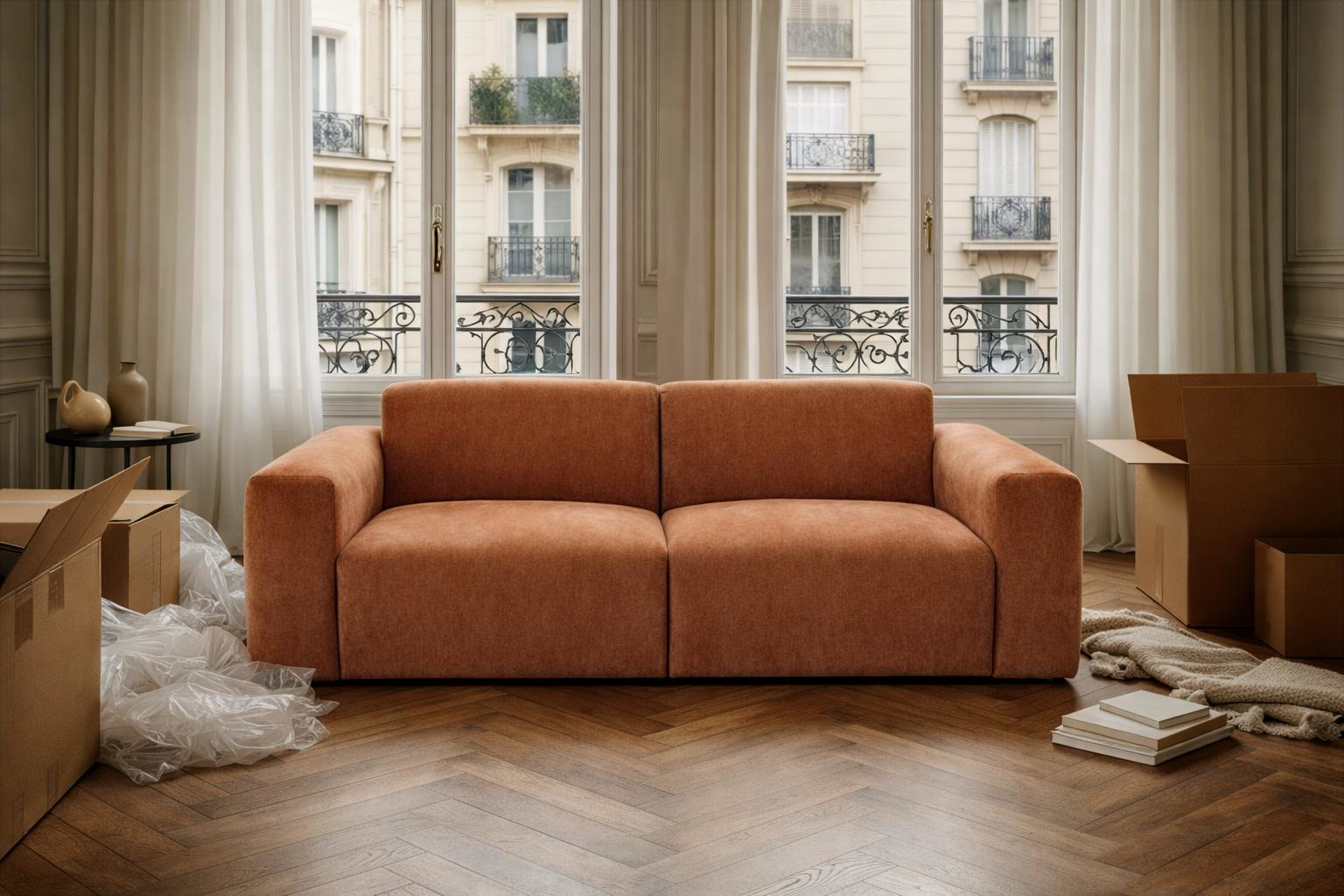 Canapé Seine Paname Avenue en tissu chenille terracotta en cours de déballage dans un salon d’appartement parisien avec parquet et cartons de livraison