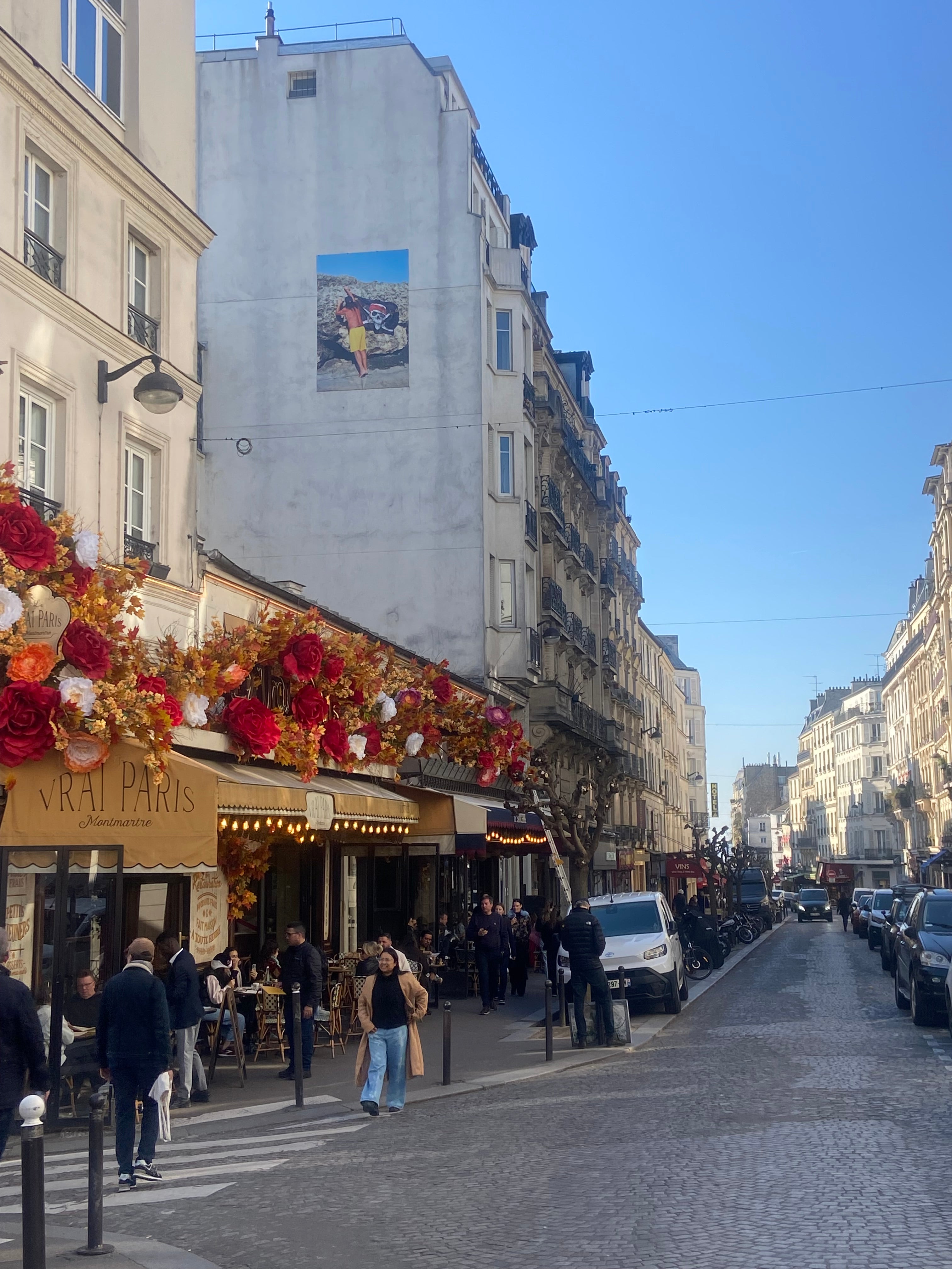 Rue des Abbesses à Montmartre Paris avec terrasse de café fleurie et ambiance animée
